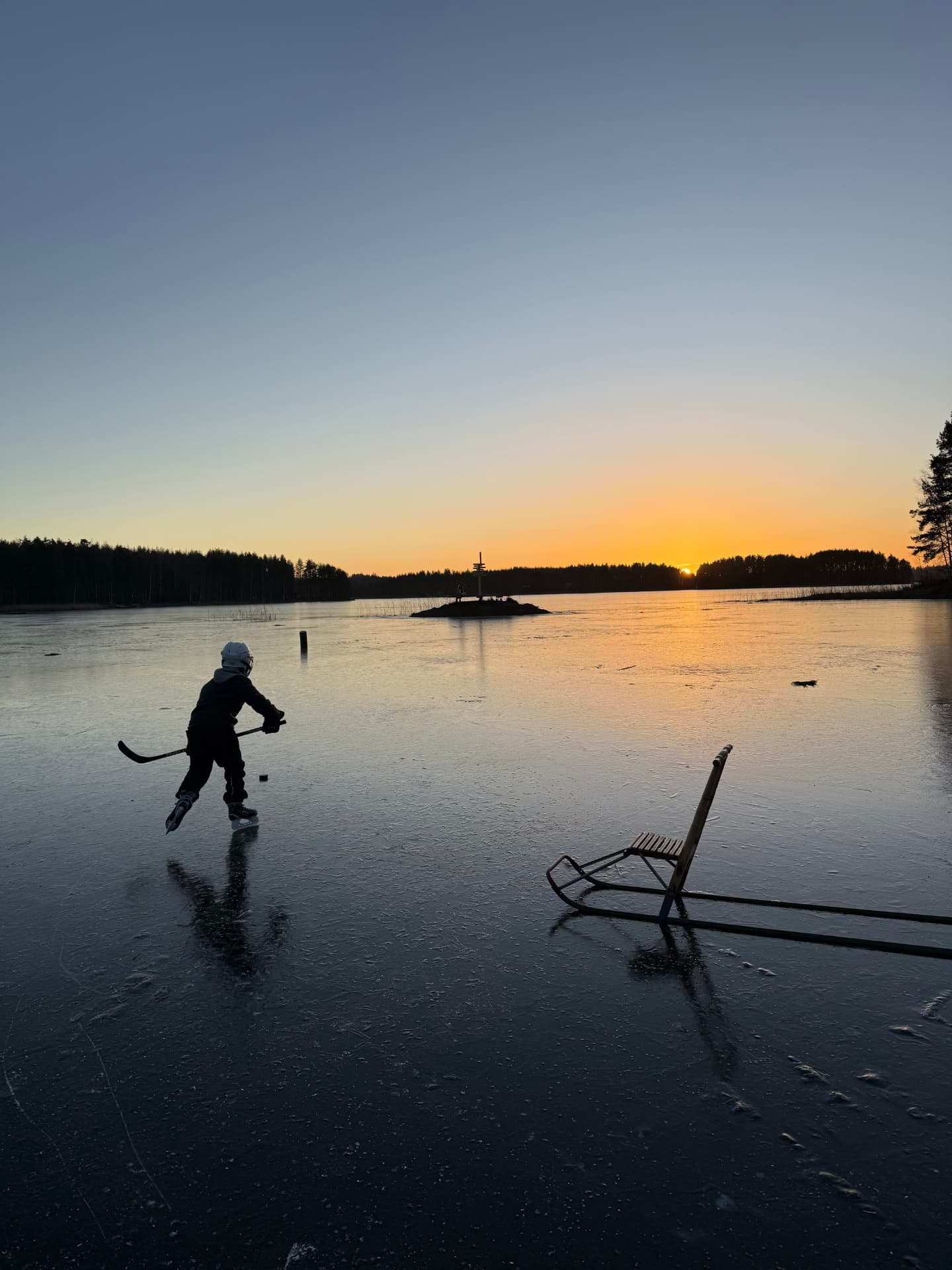 Luistelua järven jäällä auringonlaskussa